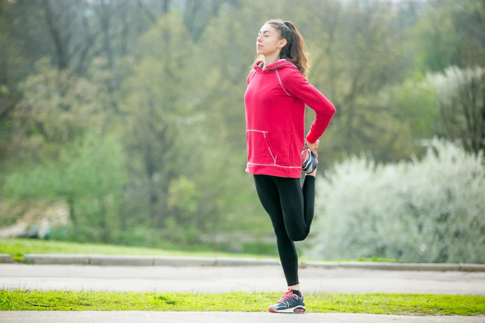 Mujer estirándose al aire libre, resaltando cómo el ejercicio físico regular ayuda a reducir la inflamación y mejora la salud general del cuerpo.