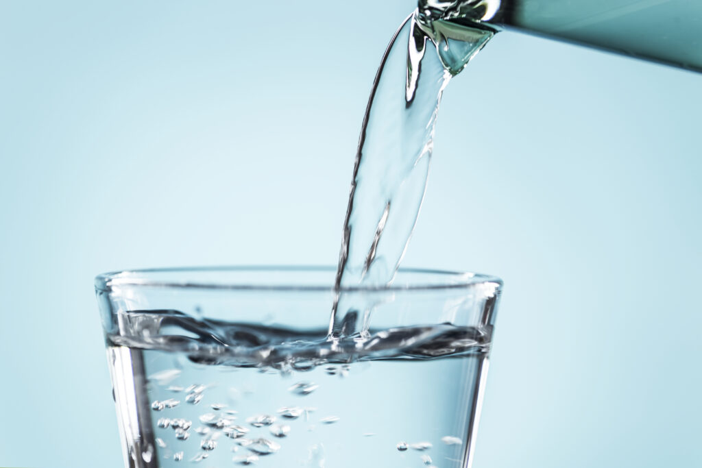Primer plano de agua siendo vertida en un vaso, perfecta para ilustrar temas sobre hidratación saludable y el consumo adecuado de agua al día